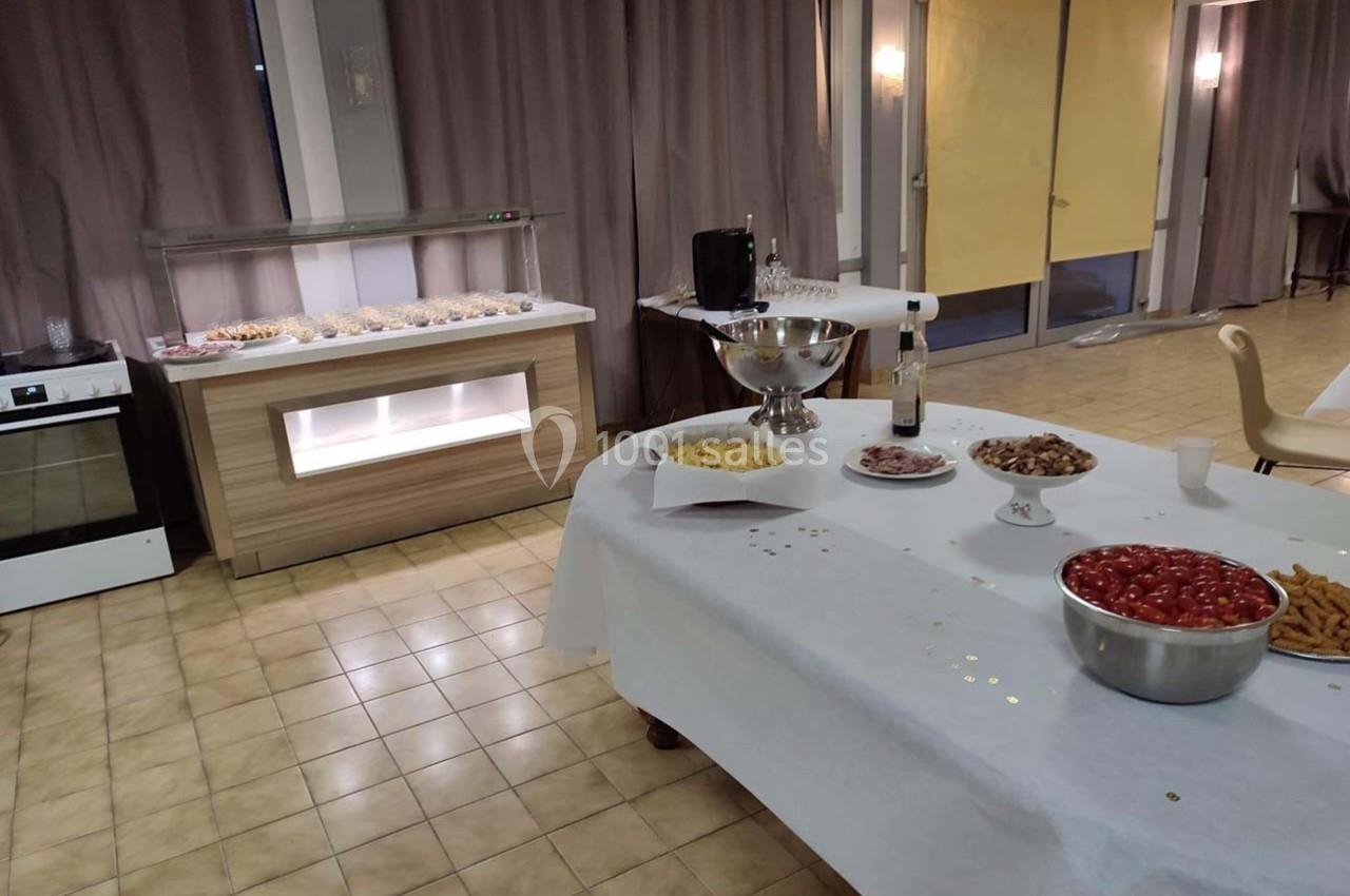 Table dressée pour un buffet avec divers plats, bols de tomates cerises, chips et amuse-bouches dans une salle éclairée.
