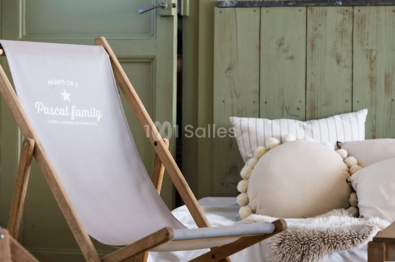 Chaise longue en bois avec tissu imprimé, placée dans un intérieur cosy avec coussins et mobilier en bois vert.