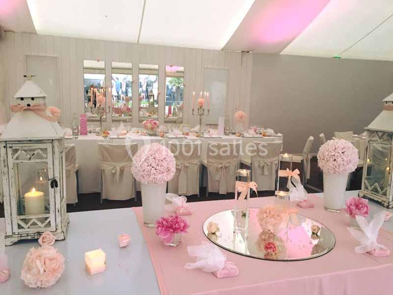 Décoration de table de mariage avec des tons roses et blancs, lanternes, bougies et compositions florales élégantes.