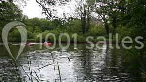 Deux personnes pagayant dans des kayaks rouges sur une rivière entourée de végétation dense.