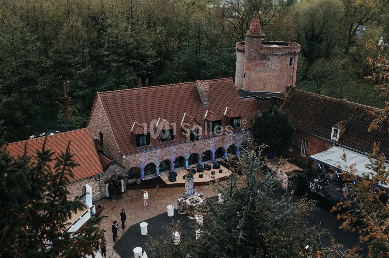 Vue aérienne d'un domaine avec une cour centrale, une fontaine, des bâtiments en briques et une petite tour.