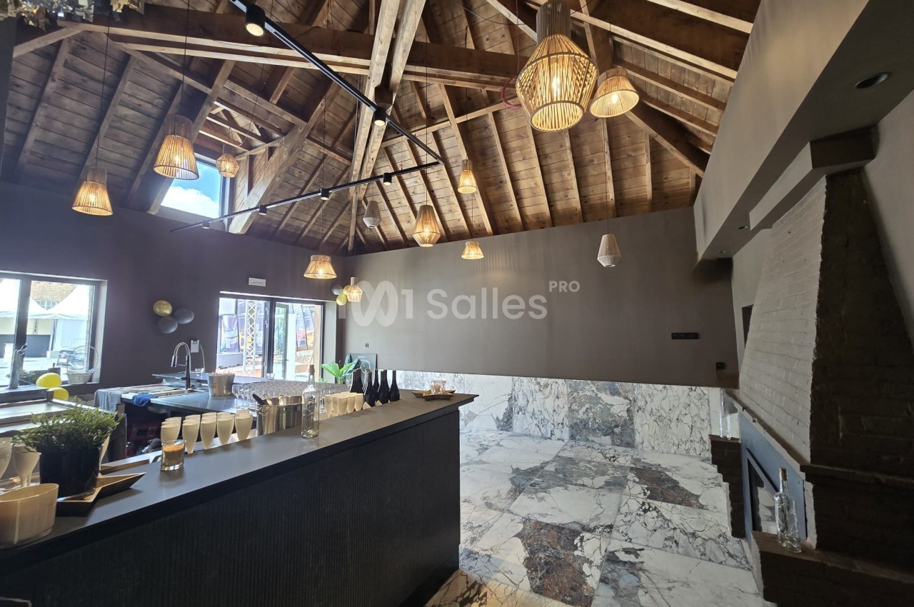 Salle avec un plafond en bois, des luminaires suspendus, un comptoir noir et un sol en marbre clair.
