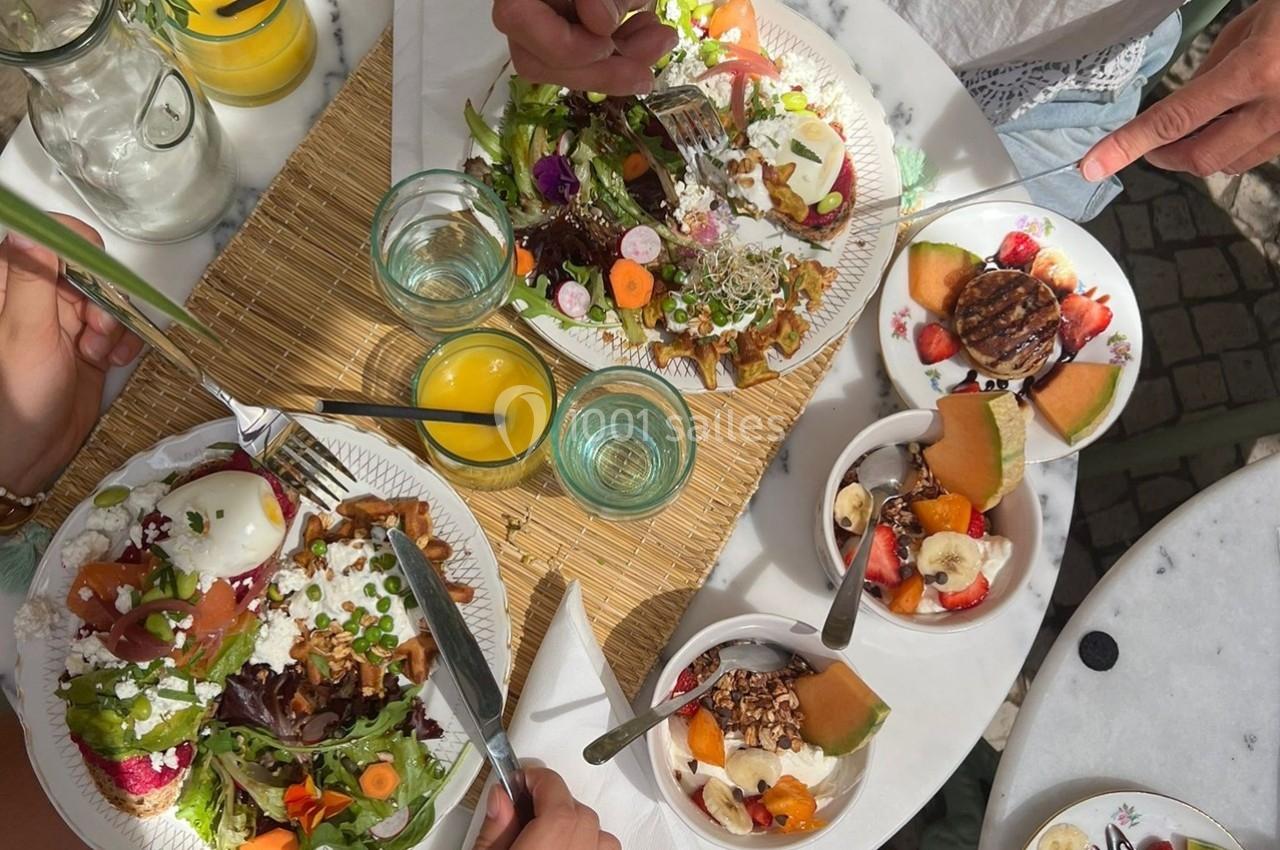 Repas composé de salades colorées, fruits frais et boissons, partagé à une table en extérieur.