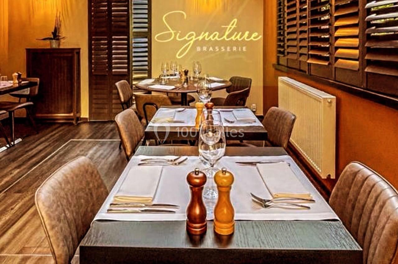 Salle de restaurant élégante avec tables dressées, lumière tamisée et décoration chaleureuse.