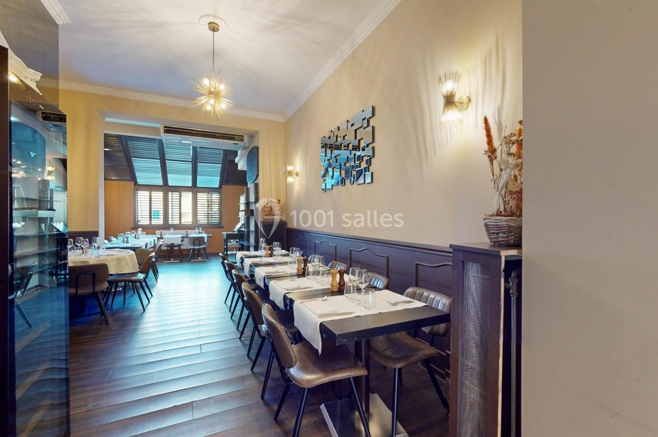 Salle de restaurant lumineuse avec tables dressées, chaises en bois et décoration murale moderne.