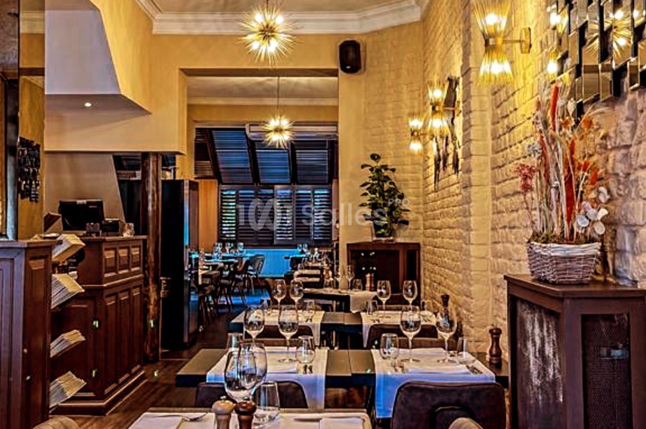 Salle de restaurant élégante avec tables dressées, murs en pierre, éclairage chaleureux et décoration florale.