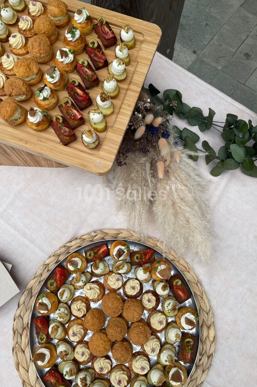 Plateaux de bouchées apéritives variées, disposés sur une table avec décoration végétale et pampas séchées.
