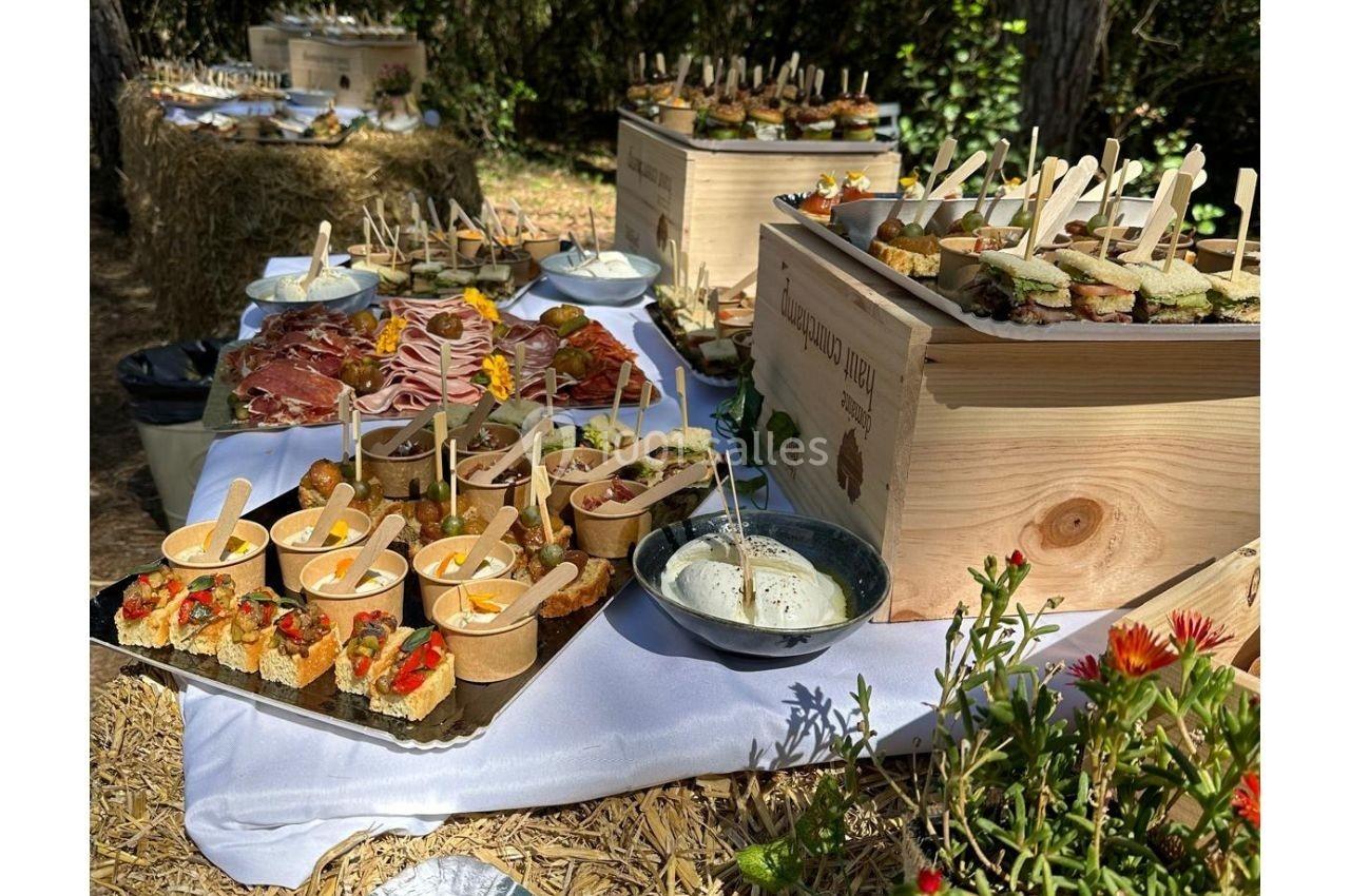 Buffet en plein air avec des amuse-bouches variés, des planches de charcuterie et des fromages sur des tables en bois.