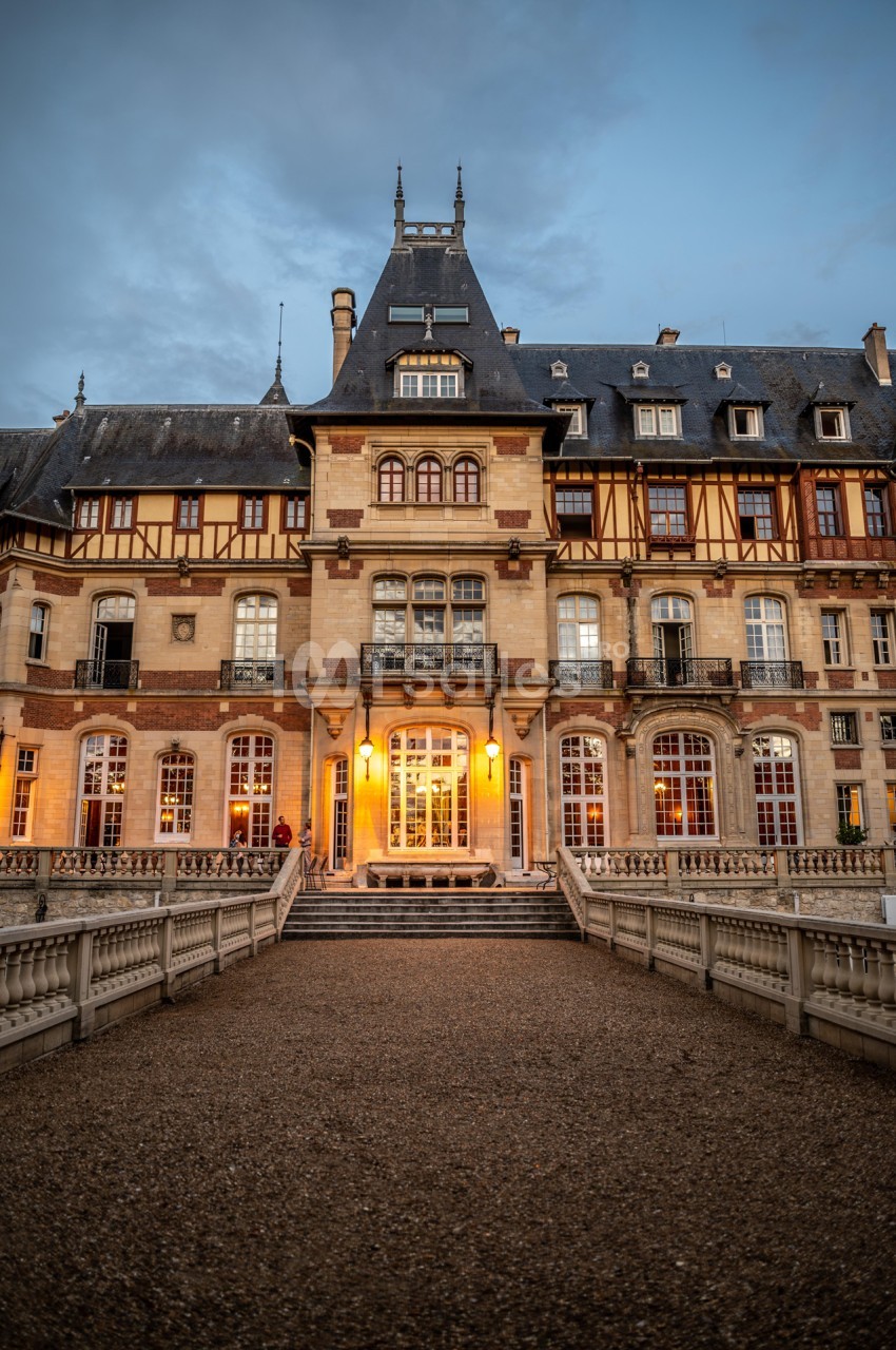 Façade d'un bâtiment historique avec des détails en pierre et bois, éclairé à la tombée de la nuit.