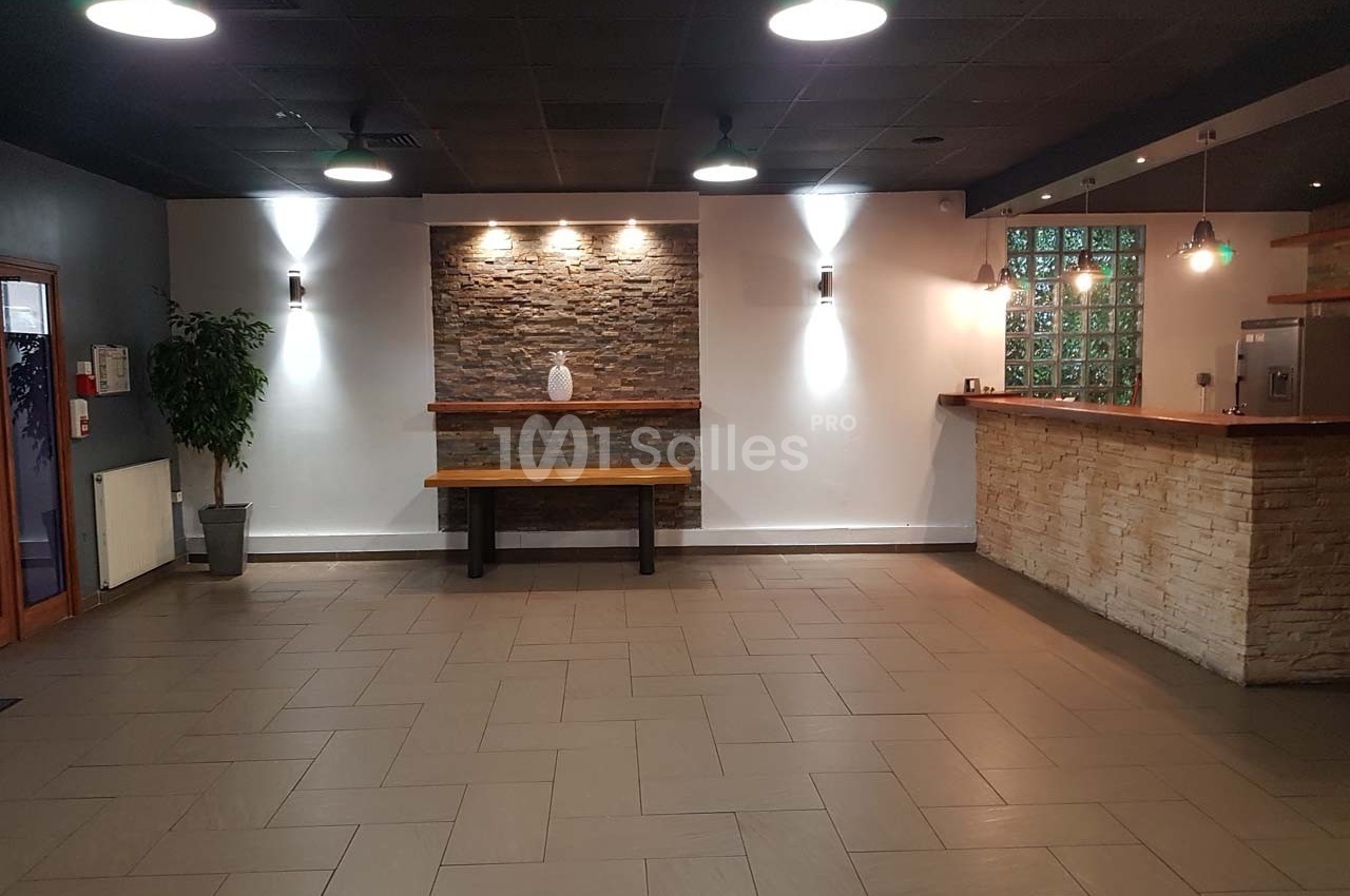 Salle vide avec murs en pierre et carrelage beige, éclairée par des appliques murales et des suspensions au plafond.