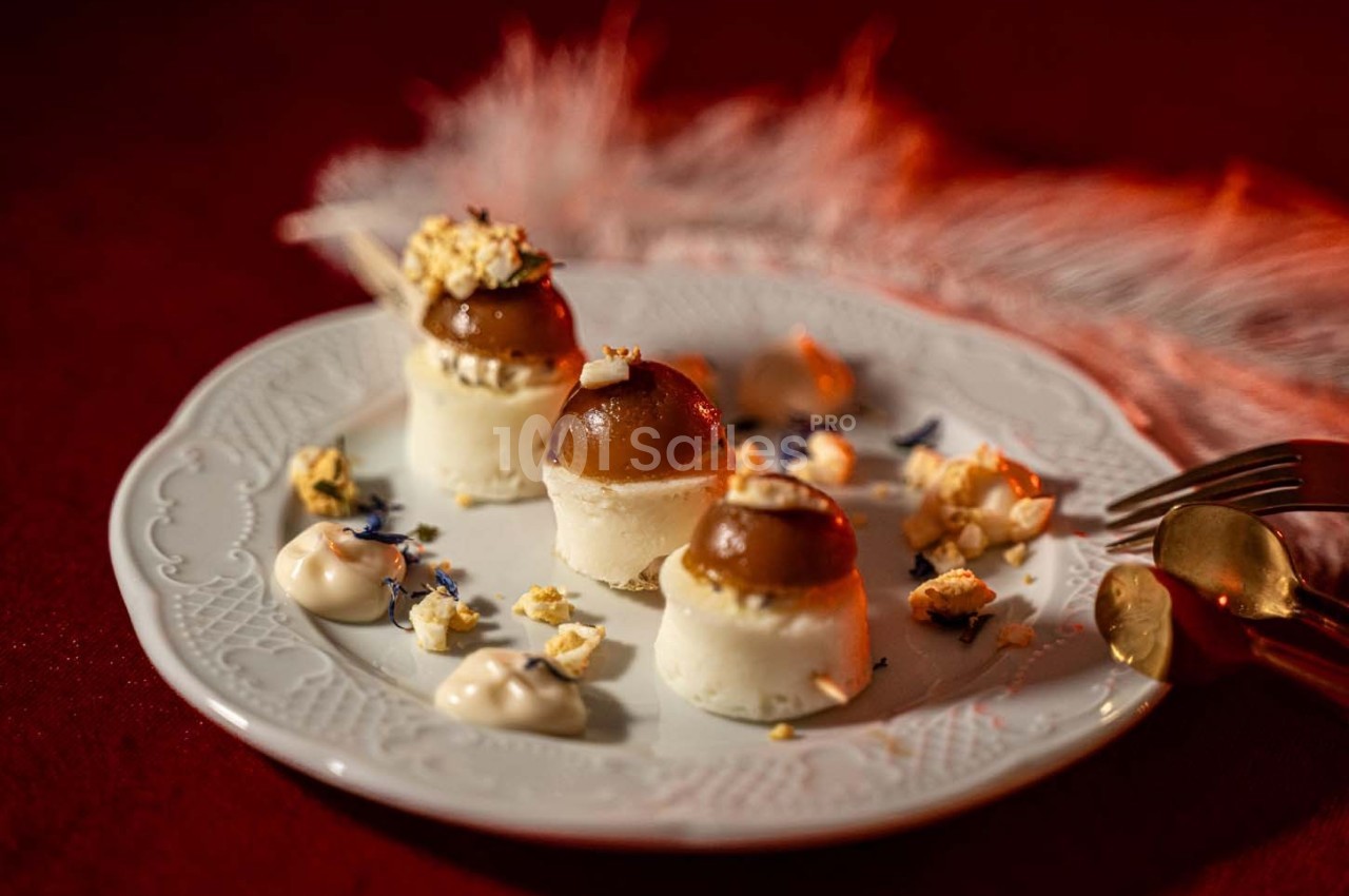Assiette de desserts raffinés avec mousse, éclats de maïs soufflé et crème, présentée sur une nappe rouge.