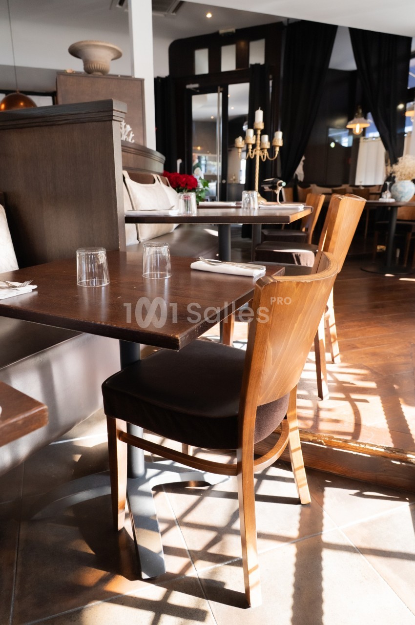 Salle de restaurant lumineuse avec tables en bois, chaises assorties et décoration élégante.