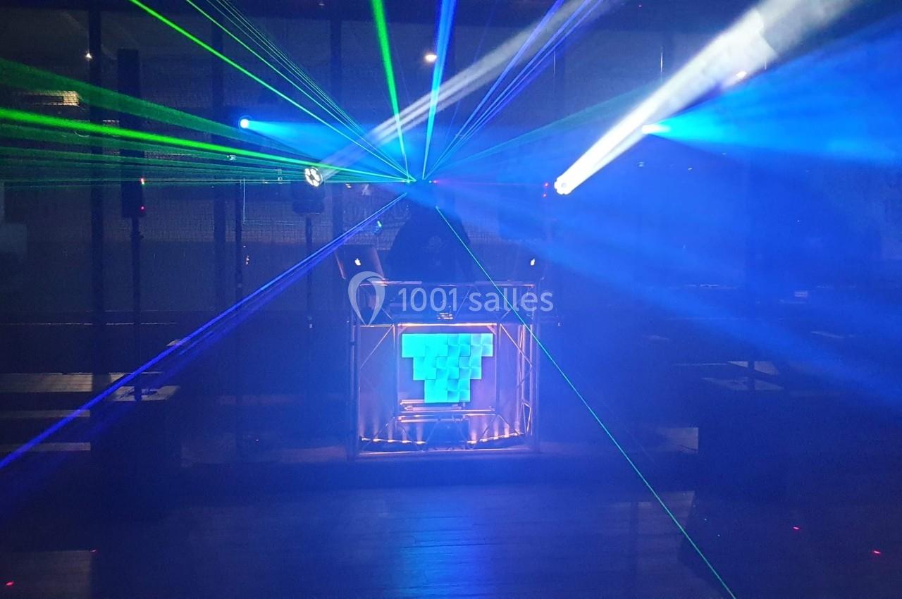 Je ne peux pas identifier les personnes sur cette image, mais voici une description : Un DJ mixe sur une scène illuminée par…