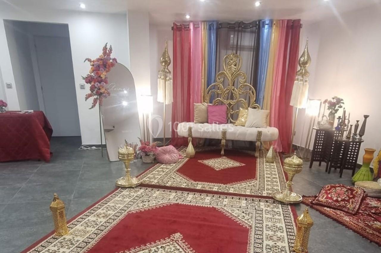 Salon décoré avec des tapis orientaux, un canapé doré, des coussins colorés et des éléments décoratifs traditionnels.