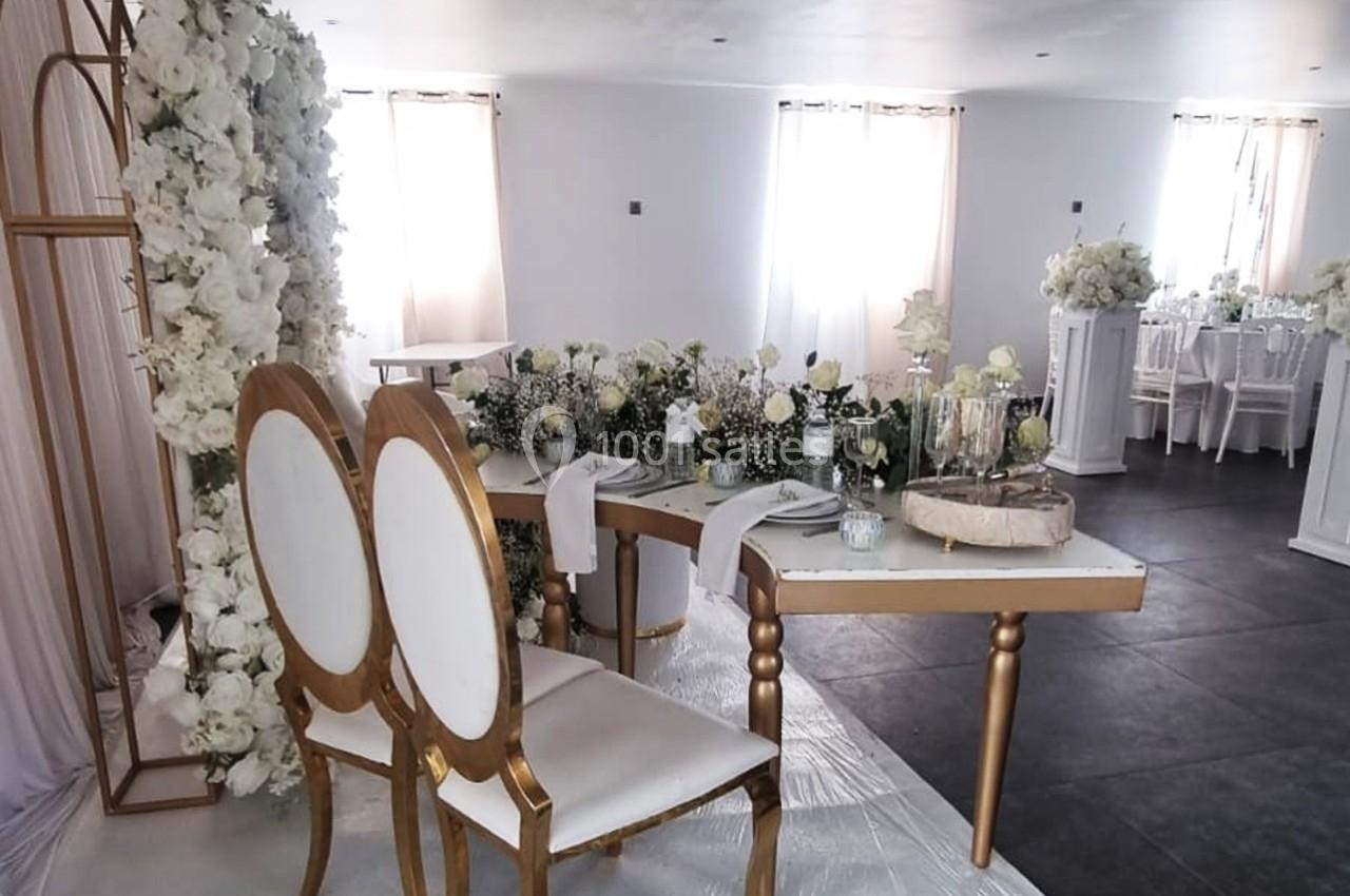 Deux chaises élégantes devant une table décorée de fleurs blanches dans une salle lumineuse.
