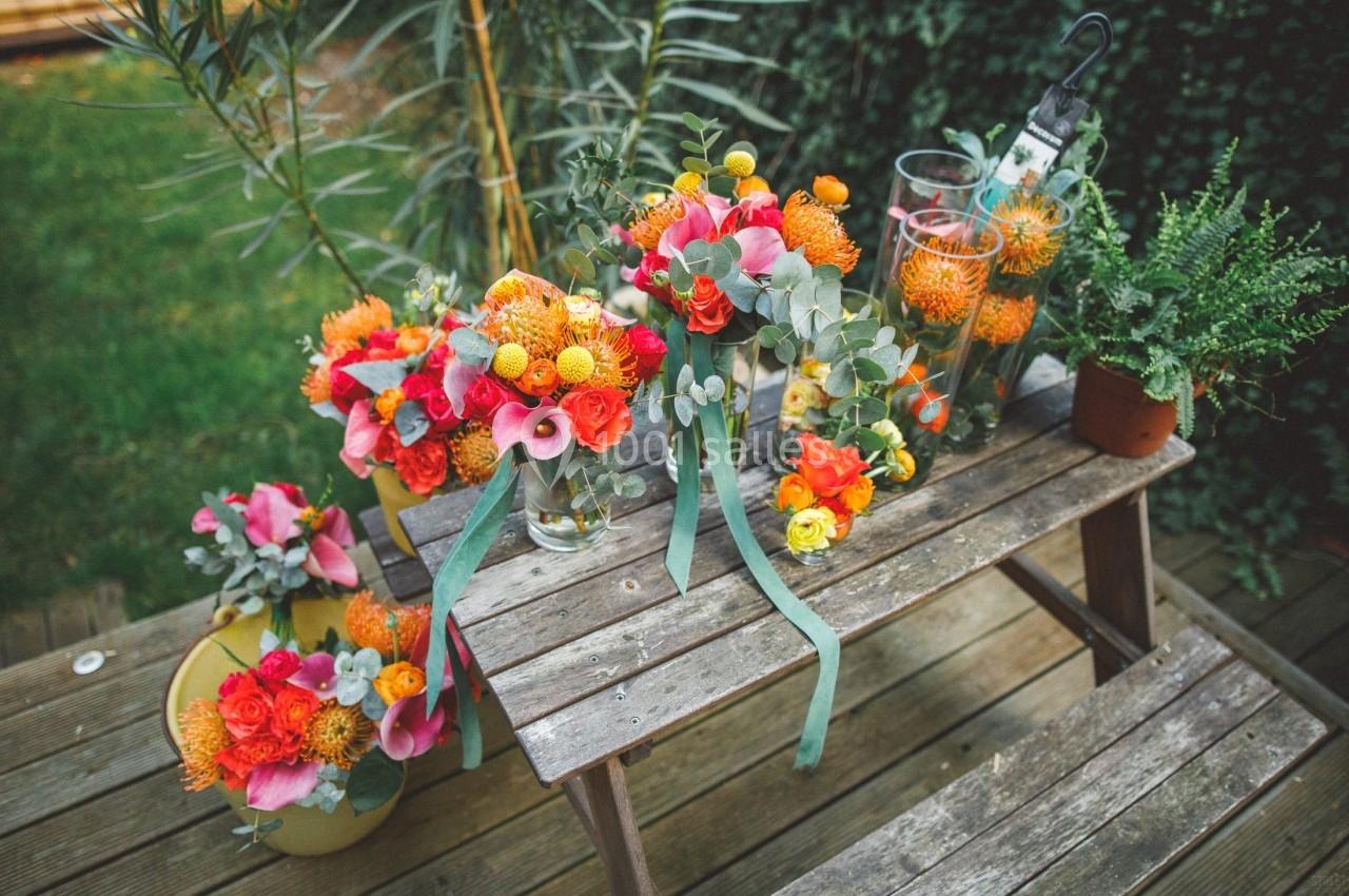 Bouquets colorés de fleurs fraîches disposés sur une table en bois dans un jardin verdoyant.