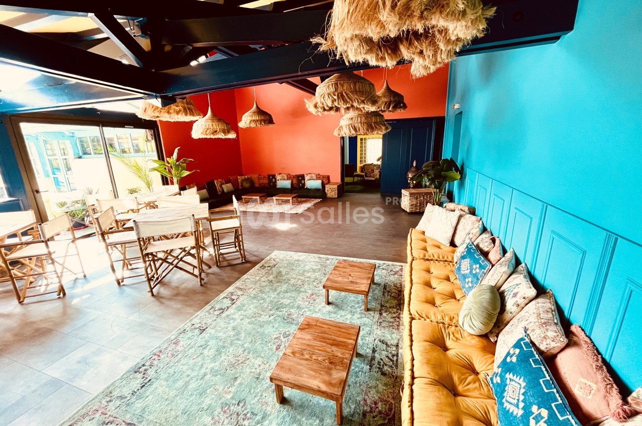 Salle lumineuse avec murs colorés, mobilier en bois, tapis décoratifs et luminaires suspendus en fibres naturelles.