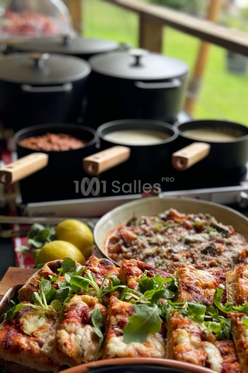Plats variés comprenant des pizzas garnies de roquette et un plat mijoté, avec des casseroles en arrière-plan.