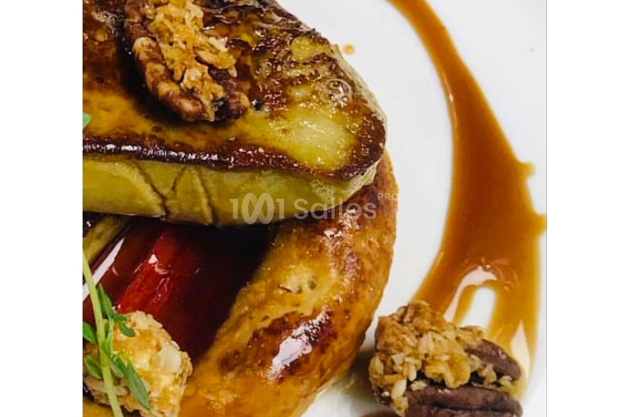 Tranche de foie gras poêlé sur une brioche, accompagnée de noix caramélisées et d'un filet de sauce.