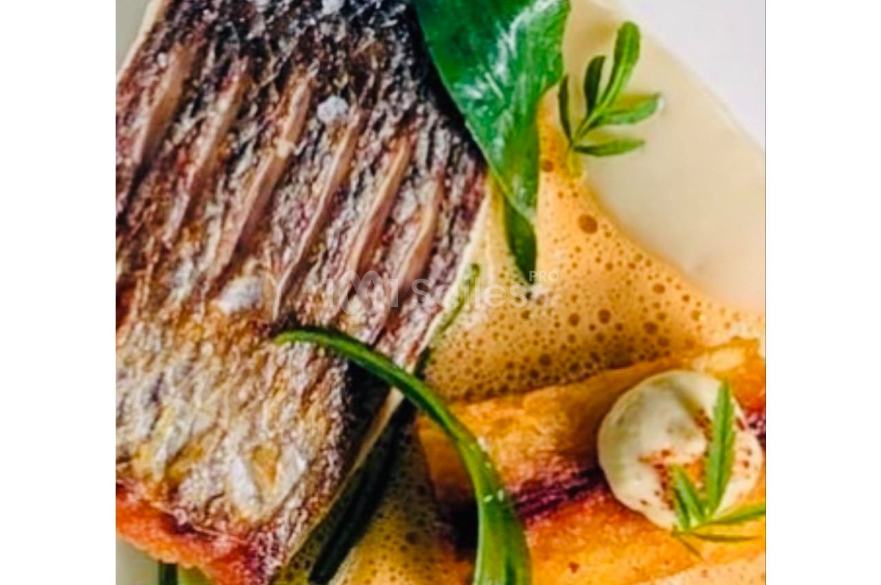 Plat gastronomique composé de poisson grillé, garnitures végétales, mousse légère et sauce crémeuse.