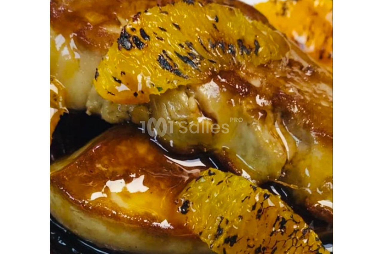 Foie gras poêlé nappé de sauce, accompagné de tranches d'orange caramélisées.