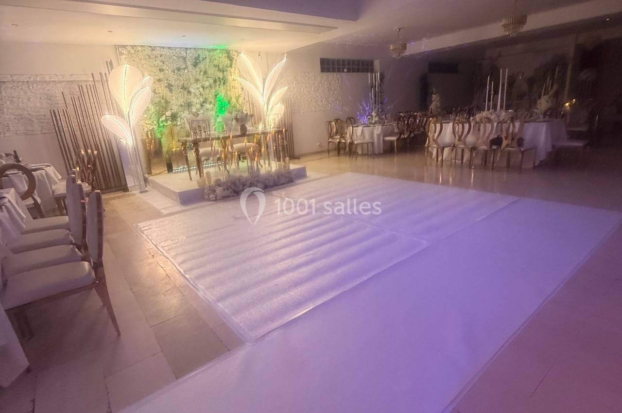 Salle de réception décorée avec des tables dressées, des chaises élégantes et un espace central lumineux.