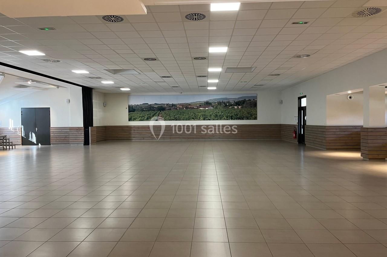 Salle spacieuse avec carrelage clair, murs en bois et fresque murale représentant un paysage de vignobles.