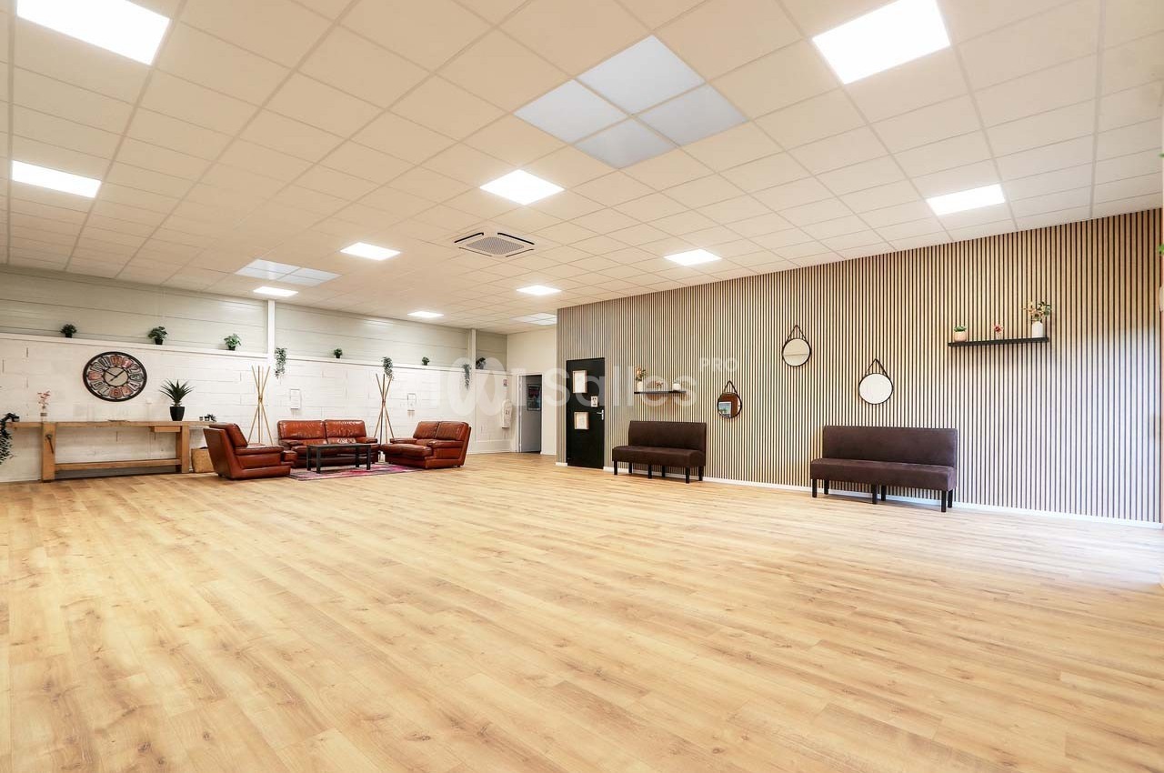Salle spacieuse avec parquet clair, murs décorés de miroirs et étagères, mobilier minimaliste et lumière naturelle.