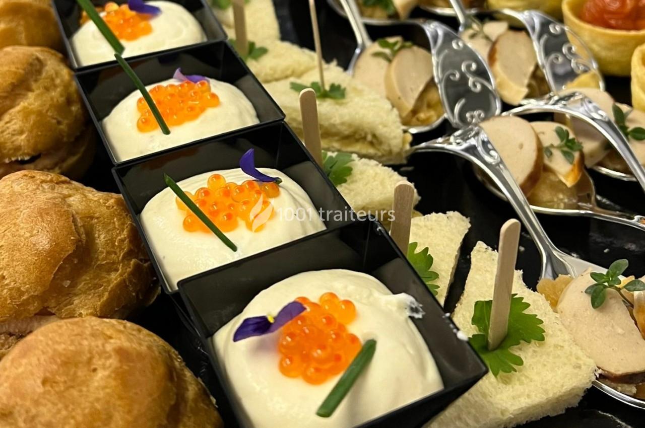 Assortiment de bouchées apéritives comprenant mousse, œufs de poisson, pains garnis et cuillères de foie gras.