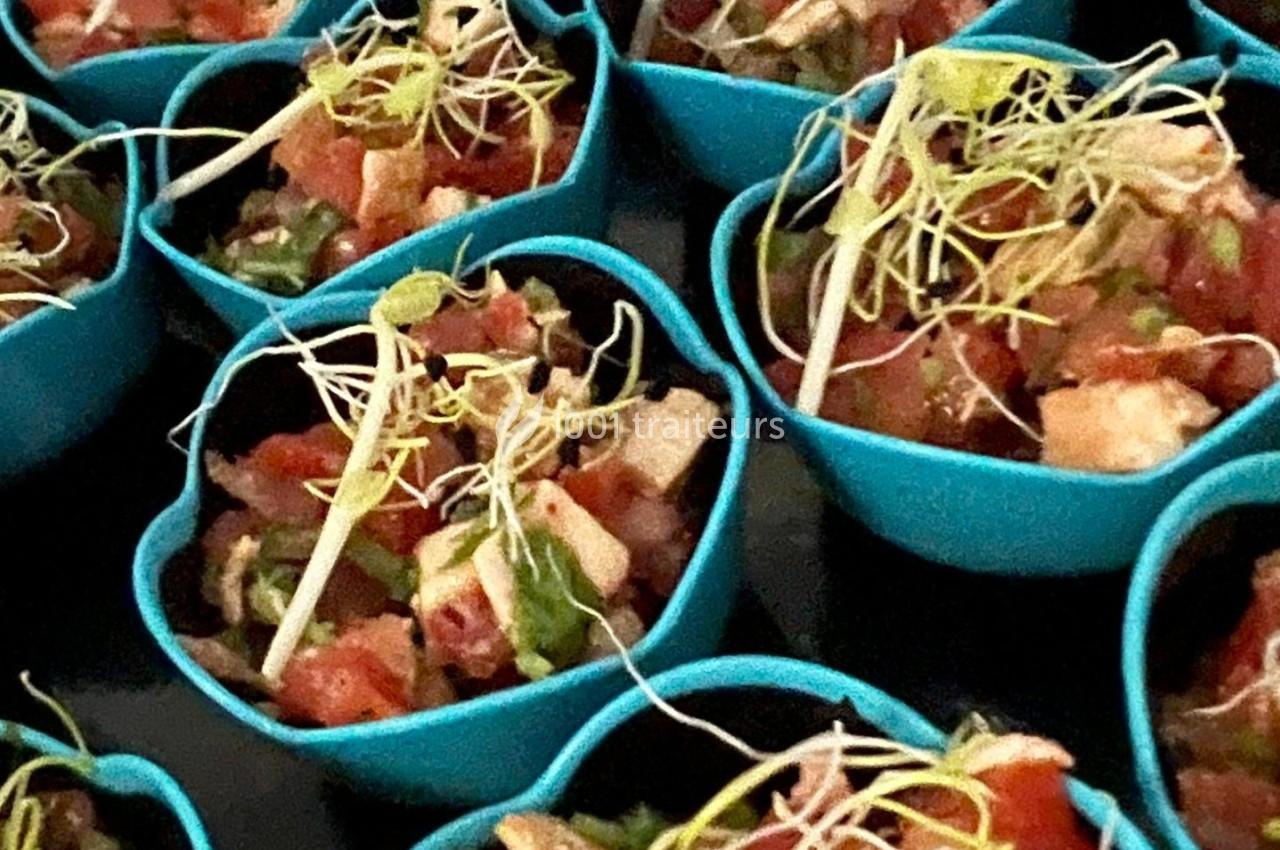 Coupelles bleues contenant une salade colorée à base de légumes, dés de fromage et pousses germées.