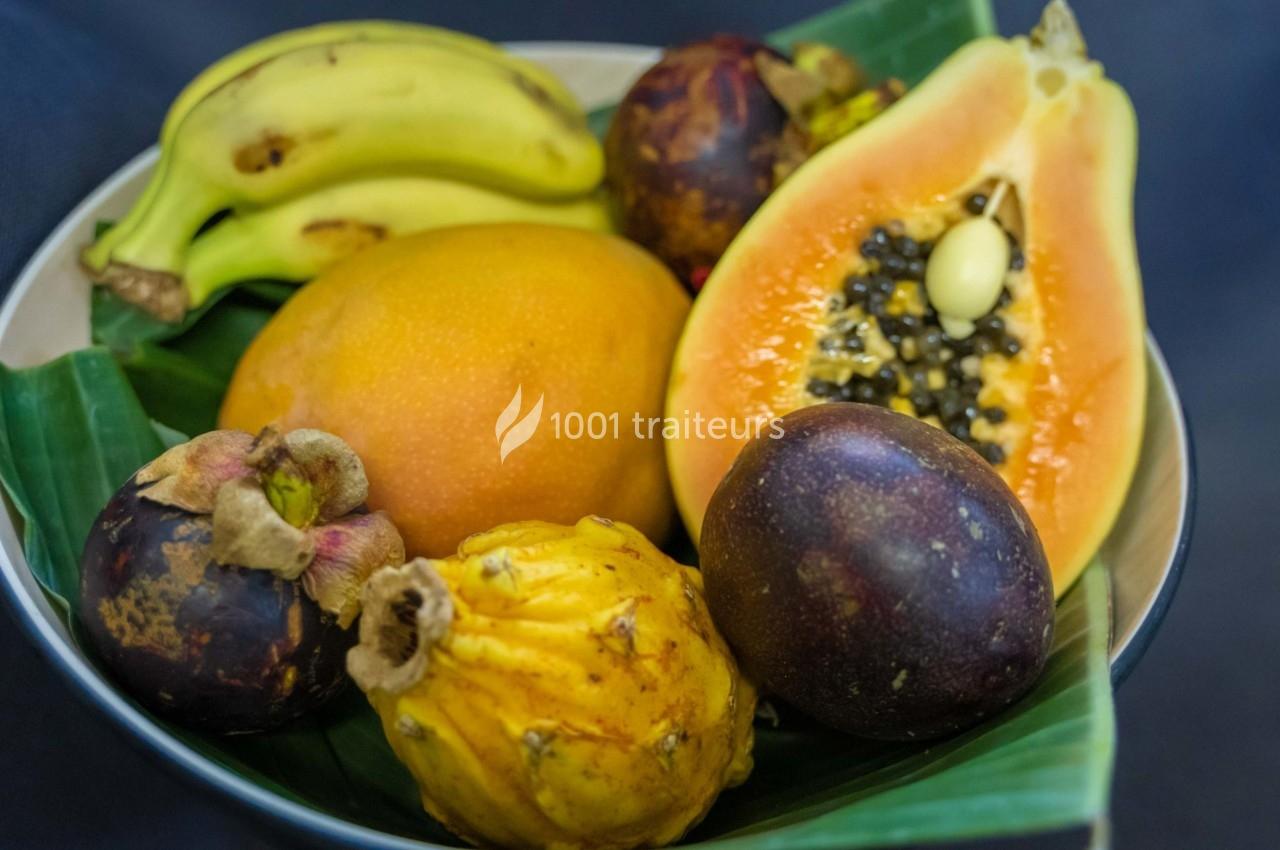 Assortiment de fruits tropicaux comprenant bananes, papaye, mangoustan, fruit de la passion et pitaya sur une feuille verte.