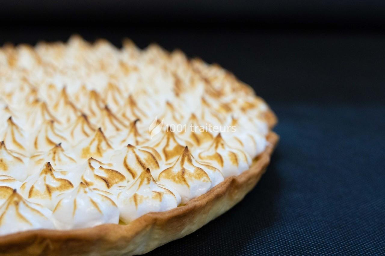 Tarte au citron meringuée avec une meringue dorée et légèrement grillée sur un fond noir.