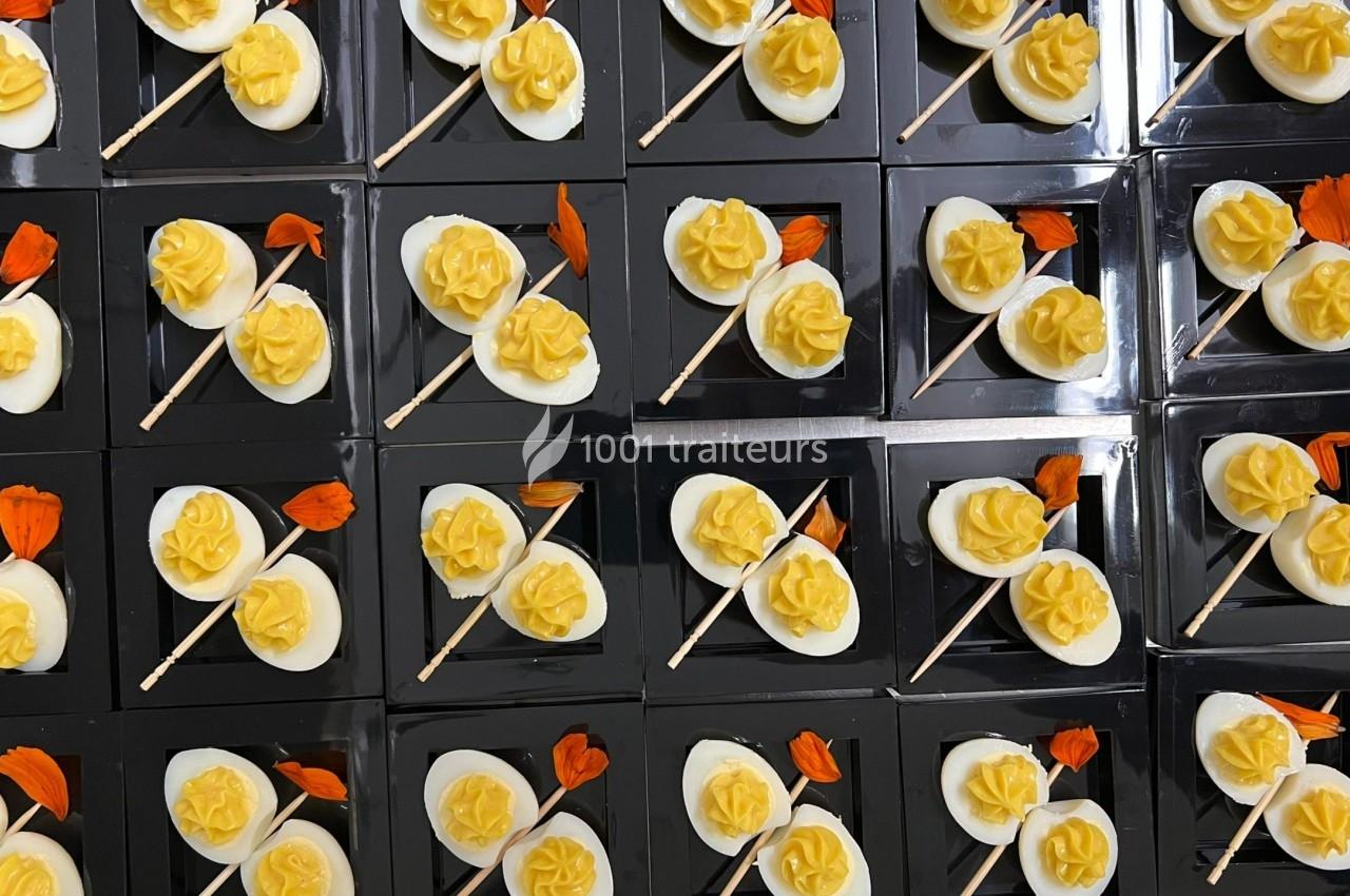 Plateaux de desserts individuels avec des fleurs jaunes en crème et des décorations orange sur fond noir.