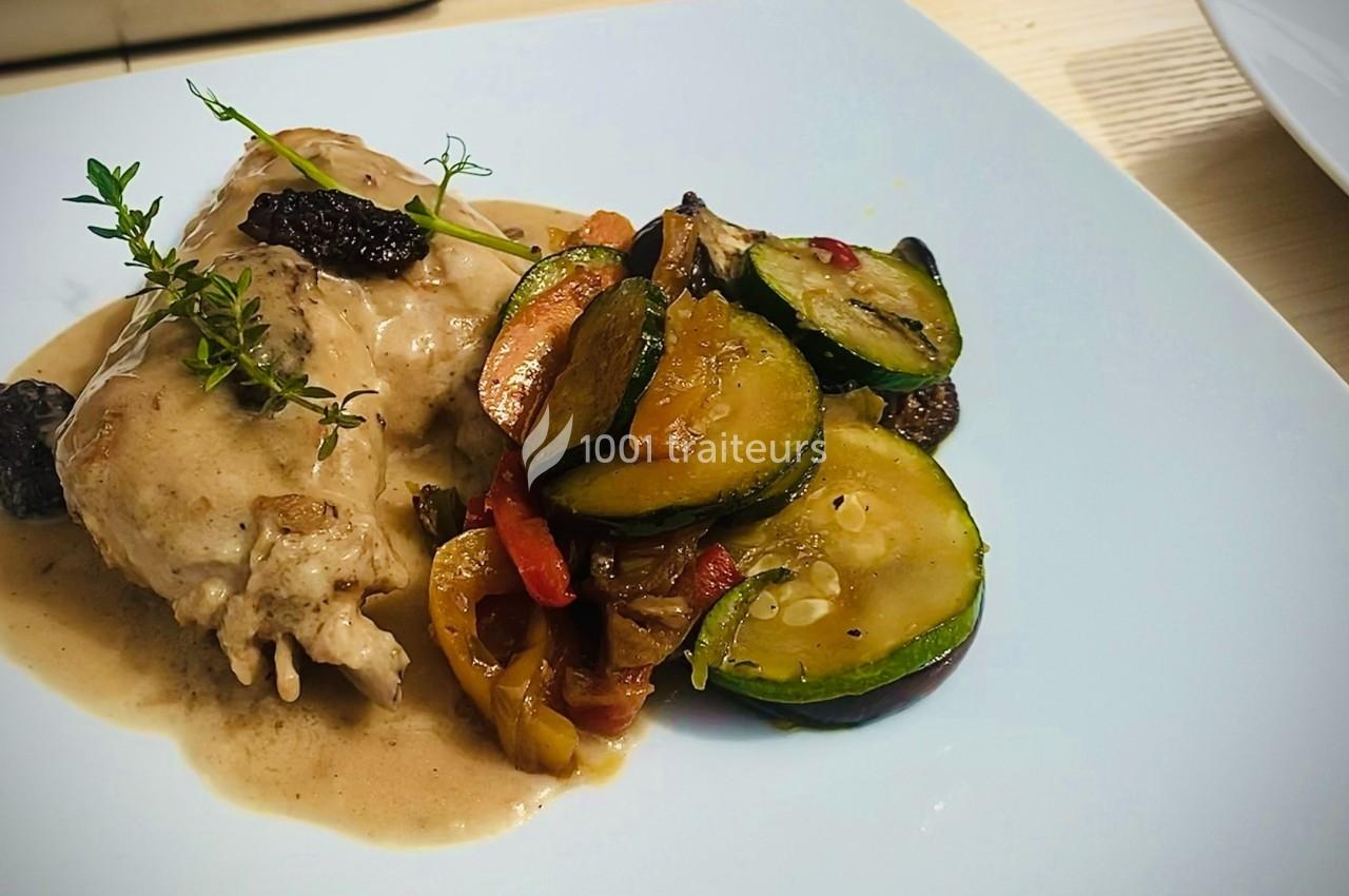 Assiette avec un suprême de volaille en sauce, garni de légumes sautés colorés et décoré de brins de thym.