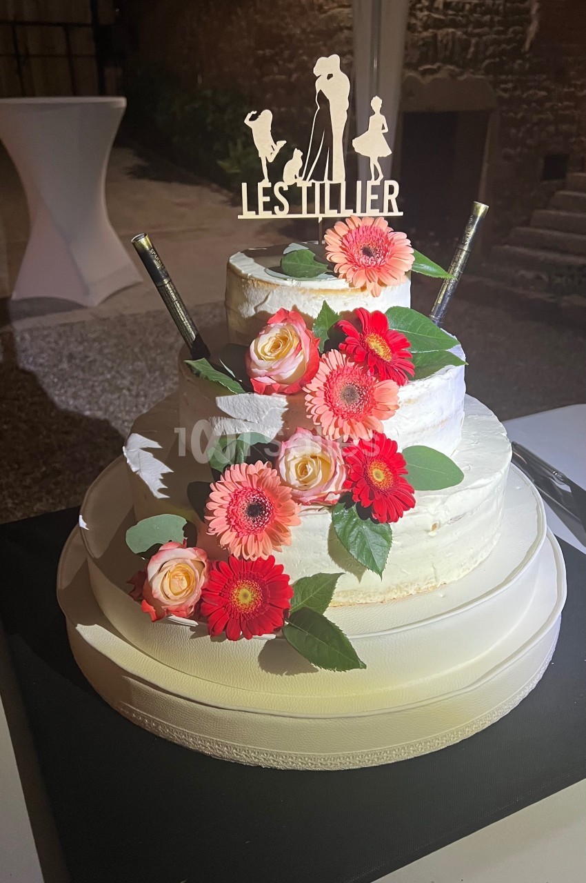 Gâteau de mariage à trois étages décoré de fleurs roses et oranges, avec un topper personnalisé ’Les Tillier’.