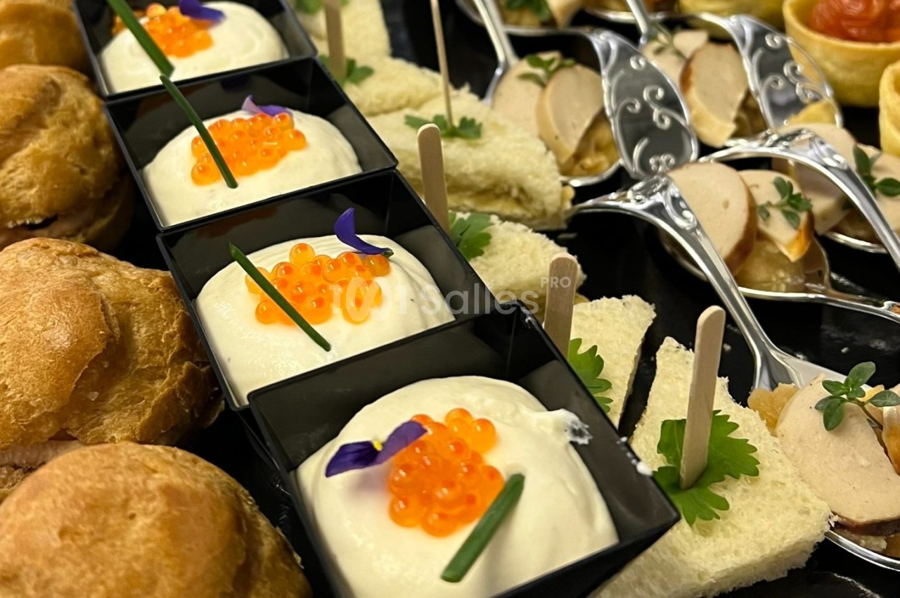 Assortiment de bouchées apéritives comprenant mousse, œufs de poisson, pains garnis et cuillères de foie gras.