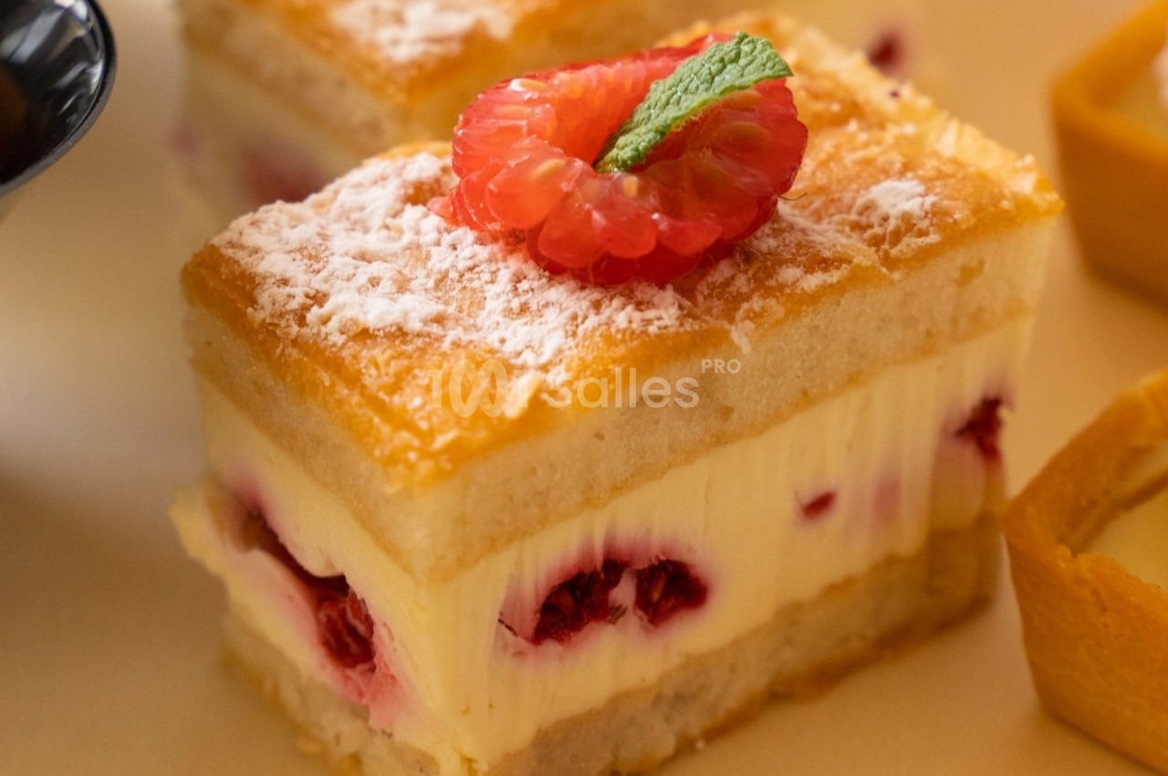 Gâteau à étages avec crème, framboises fraîches, sucre glace et une garniture de framboise et feuille de menthe.