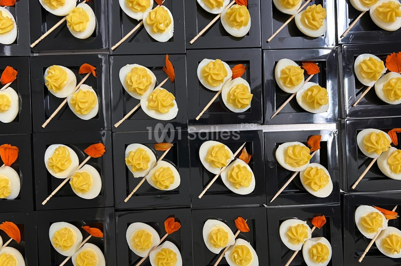 Plateaux de desserts individuels avec des fleurs jaunes en crème et des décorations orange sur fond noir.