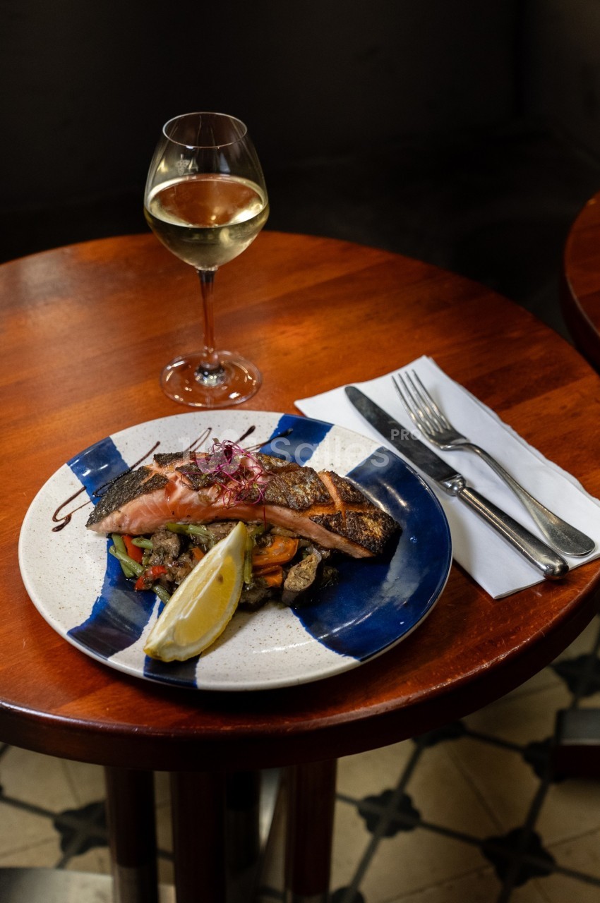 Assiette de saumon grillé avec légumes et citron, servie sur une table en bois, accompagnée d'un verre de vin blanc.