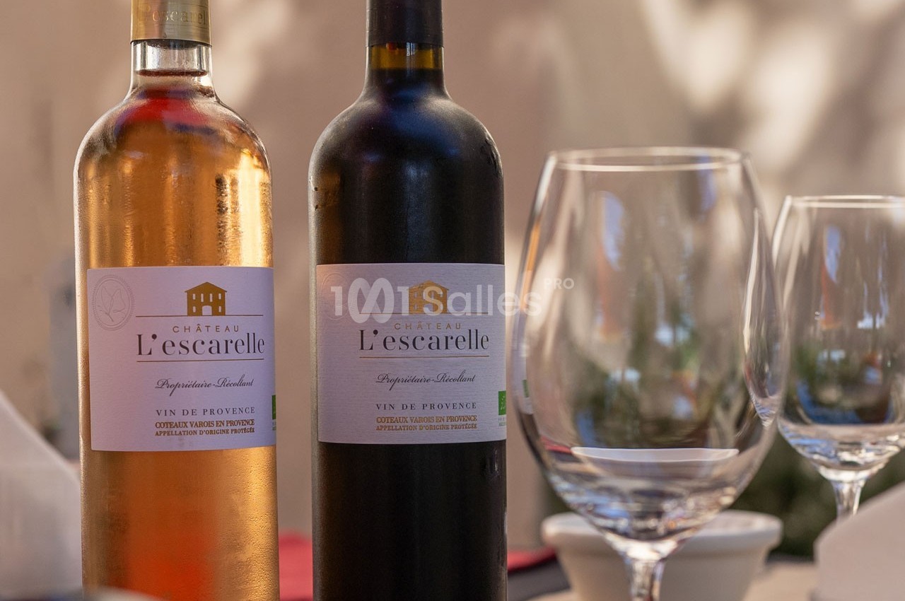 Deux bouteilles de vin Château L'Escarelle, rouge et rosé, posées sur une table avec des verres à vin vides.