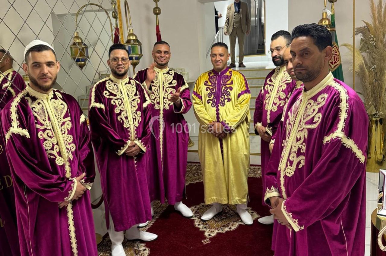 Des hommes vêtus de djellabas traditionnelles, majoritairement violettes, posent dans une pièce décorée.