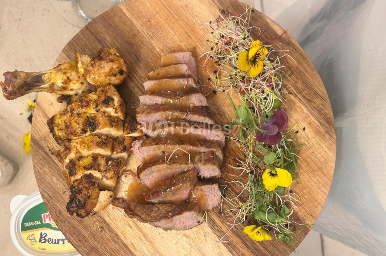 Assiette en bois avec cuisse de poulet grillée, tranches de viande sauce, jeunes pousses et fleurs comestibles.