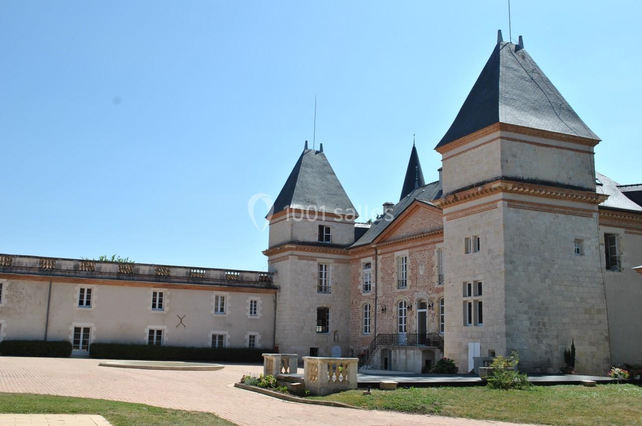 Château en pierre avec deux tours et une cour pavée sous un ciel bleu clair.