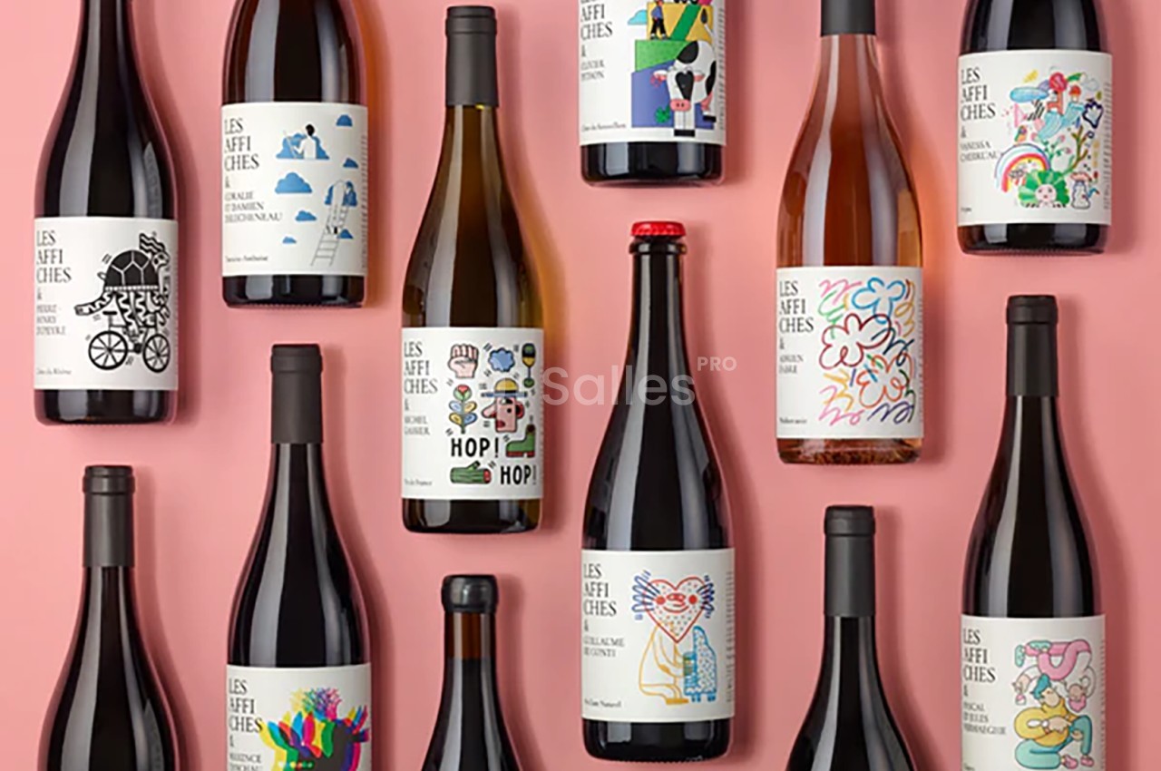 Bouteilles de vin aux étiquettes colorées et illustrées, disposées sur un fond rose.