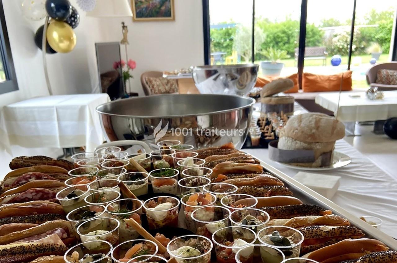 Plateau de verrines et sandwichs variés disposés sur une table lors d'un buffet dans une salle lumineuse.