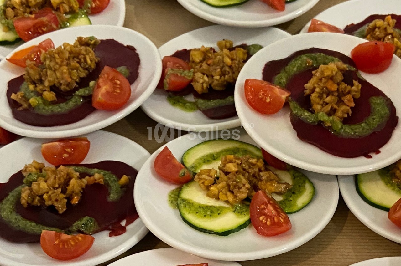 Assiettes de betteraves et courgettes garnies de pesto, noix hachées et quartiers de tomates cerises.