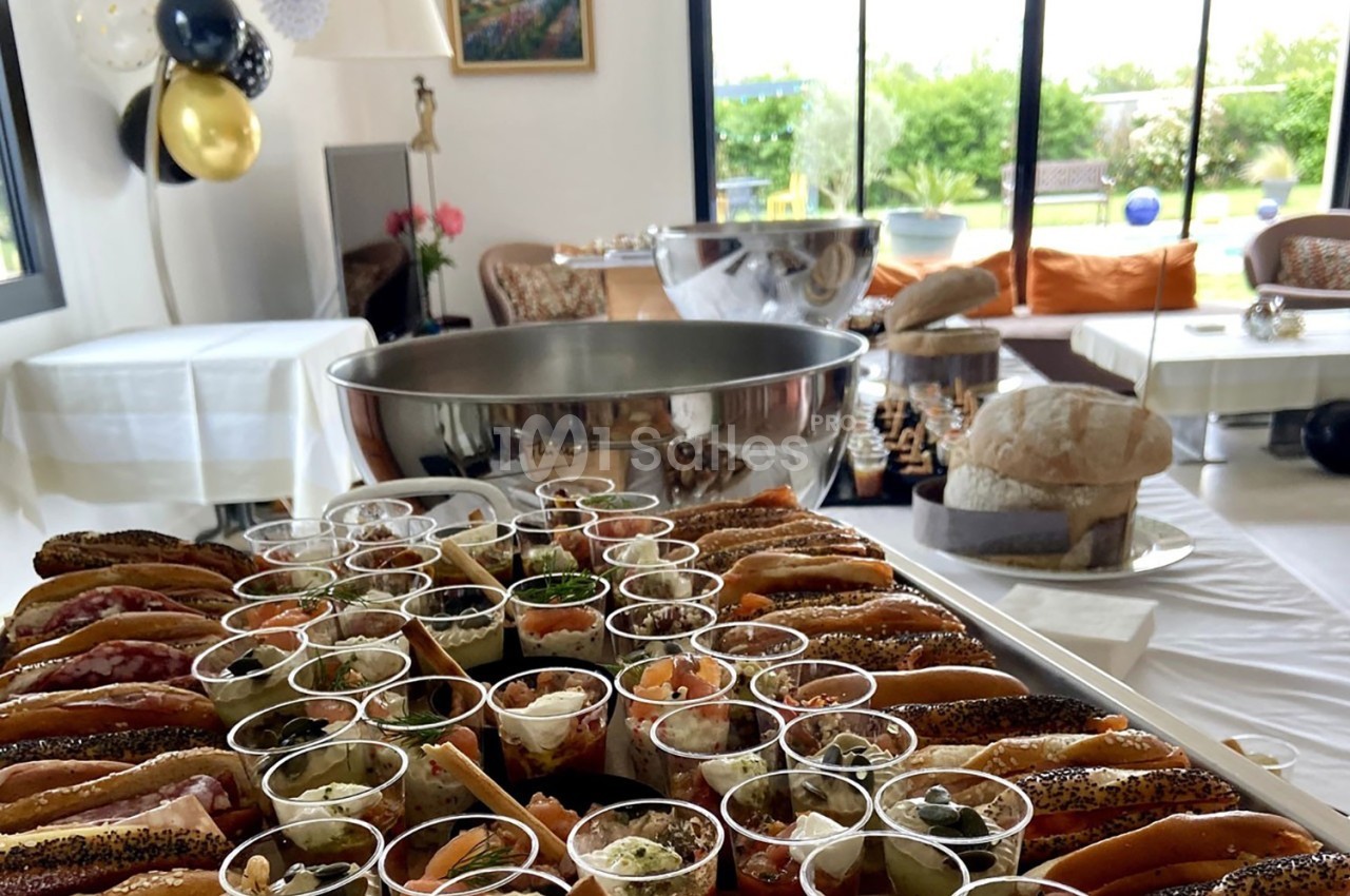 Plateau de verrines et sandwichs variés disposés sur une table lors d'un buffet dans une salle lumineuse.