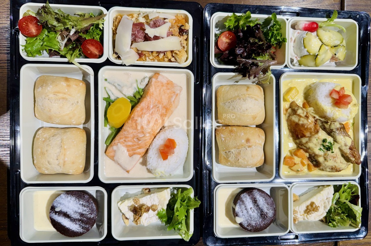 Plateaux-repas composés de saumon, poulet, légumes, riz, salades, pains, desserts et fromage.