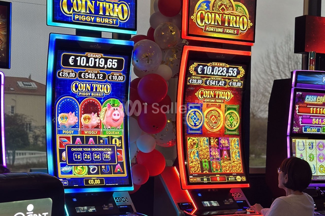 Deux machines à sous lumineuses avec écrans colorés, une personne assise devant l'une d'elles dans un casino.