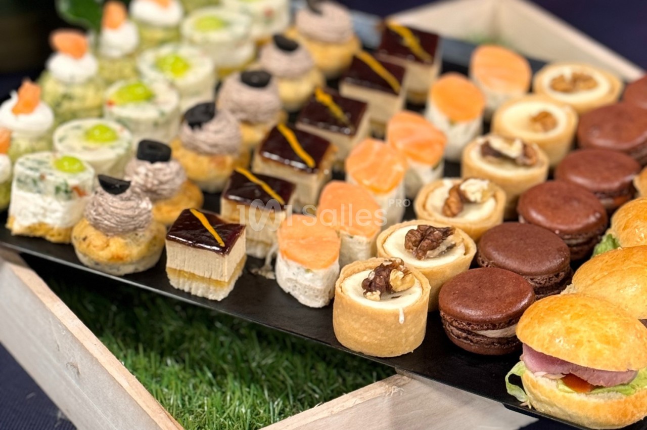Plateau de bouchées salées et sucrées variées, comprenant macarons, tartelettes, toasts et petits sandwichs.